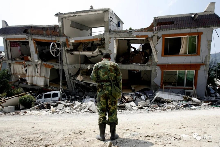 ▲2008年5月19日下午2时28分，北川，一名参加救援的战士在孤零零的危楼前默哀。图片来源 / 新京报摄影部