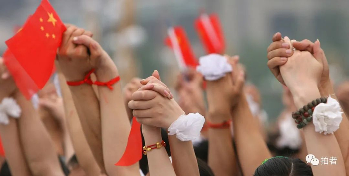 ▲2008年5月20日，成都天府广场，人群中，无数双手紧握在一起，高高举起。摄影 / 何龙盛