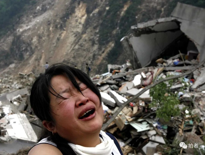 ▲2008年5月15日，北川县城，一名妇女在废墟上呼喊亲人。当日下午4点，她丈夫的遗体被发现。图片来源 / 新京报摄影部