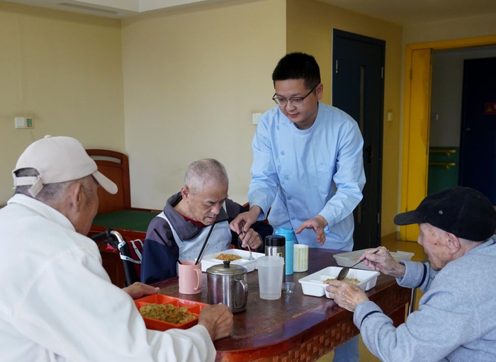 在上海市杨浦区社会福利院，护理主管王程（右二）照顾老年人们用餐（4月28日摄）。新华社记者 刘颖 摄