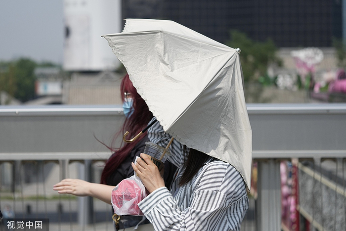 2023年5月15日，北京艳阳高照，高温蓝色预警持续，市民撑伞遮阳。 中新社记者 崔楠 摄