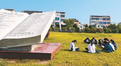 温岭市新河中学雕塑旁，学生们在上户外阅读课。郝天韵摄