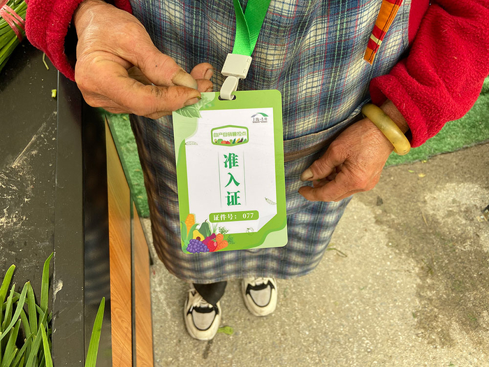 村民在疏导点卖菜需持有准入证。