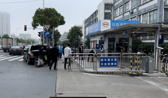 比亚迪长沙雨花工厂招聘中心门前，带着行李进出工厂的工人。摄影/刘丁