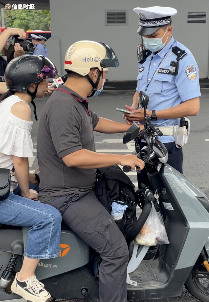 一辆电动自行车在后座搭载成年人，被交警拦下。信息时报记者 王智汛 摄
