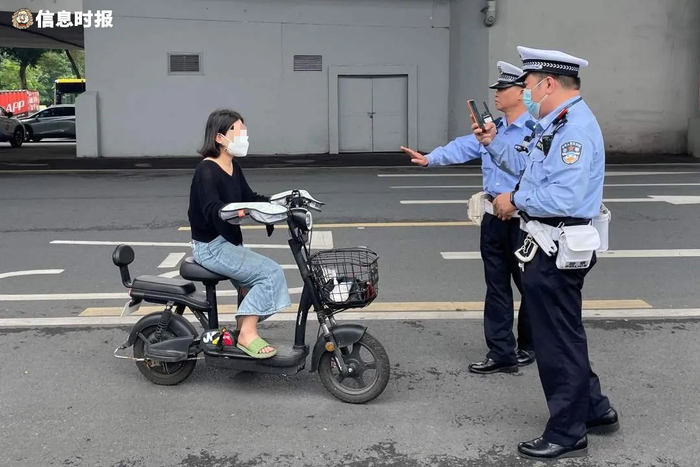 一名骑电动自行车的女子因未戴头盔，被交警拦下。信息时报记者 王智汛 摄