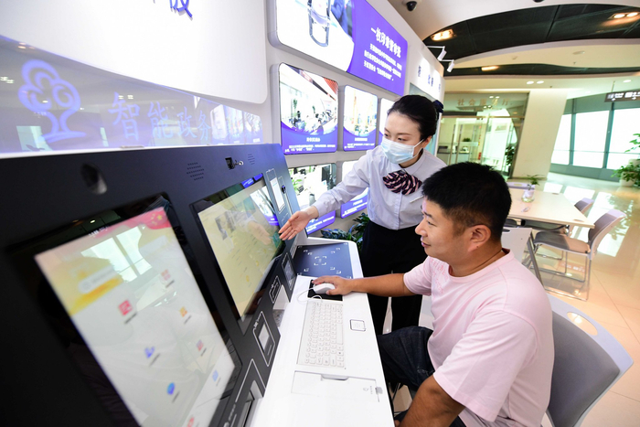 北京经开区政务服务中心自助服务机前，工作人员正在协助企业办理“跨省通办”业务。 和冠欣摄