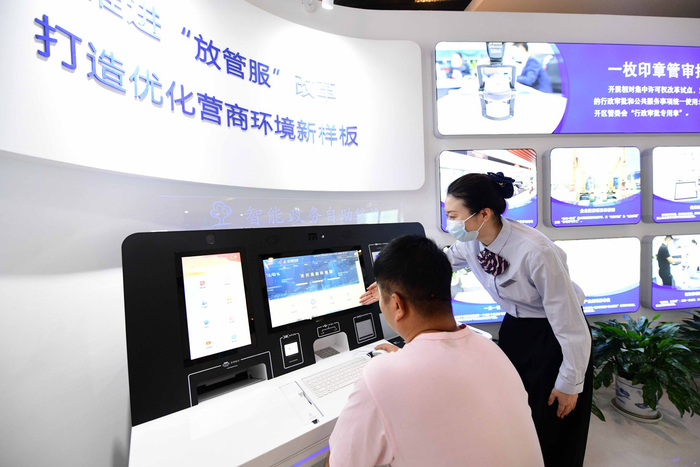 北京经开区政务服务中心自助服务机前，工作人员正在协助企业办理“跨省通办”业务。 和冠欣摄