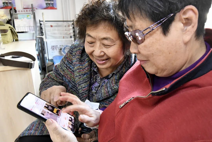 11月12日，北京市丰台区东高地街道万源南里社区的两位老人使用手机购买衣服。（图片摄于2021年）新华社记者 李欣 摄