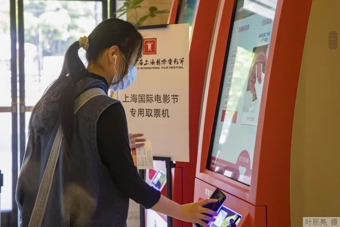 在大光明电影院，观众在专用取票机前扫码取票。 