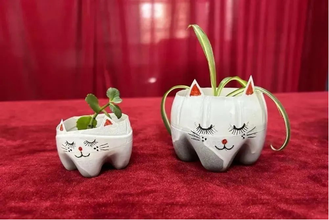 利用塑料水瓶底制作成的喵咪小花瓶。