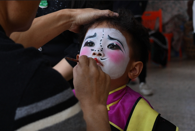 普宁南山英歌队演出前，化妆师宋才正在为“小时迁”陈楷铭上妆。农民日报·中国农网见习记者 郭诗瑀 摄