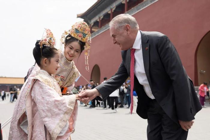 ▲5月12日，澳大利亚贸易和旅游部长法雷尔在北京参观故宫时与一名小女孩握手。（美联社）