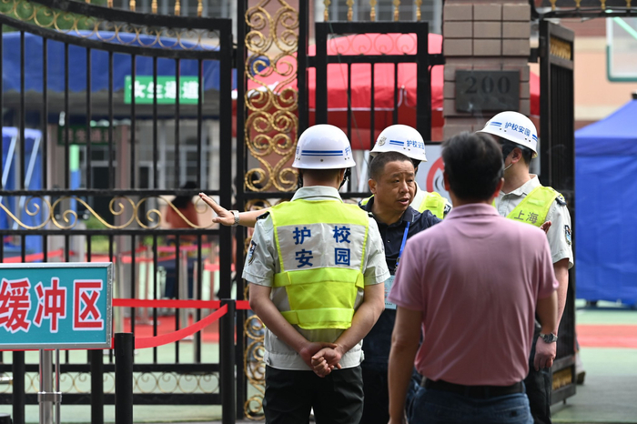 2023年6月7日，上海市第二中学，考生进入考场前，考点的工作人员正在跟安保人员说注意事项。澎湃新闻记者 吴栋 图