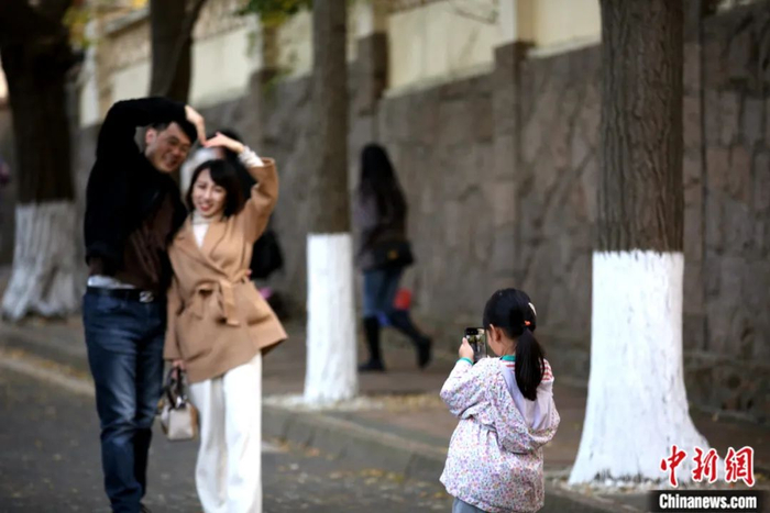 2022年11月，山东省青岛市八大关景区居庸关路，一名儿童为父母拍照留念。蔡亚群 摄