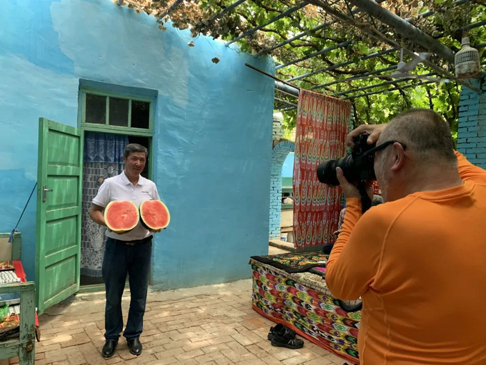 图为吐鲁番民宿老板阿不都外力向日本游客展示切好的大西瓜.邢晓婧 摄