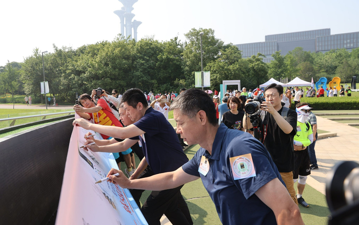 活动嘉宾在横幅上签名。新京报记者 王子诚 摄
