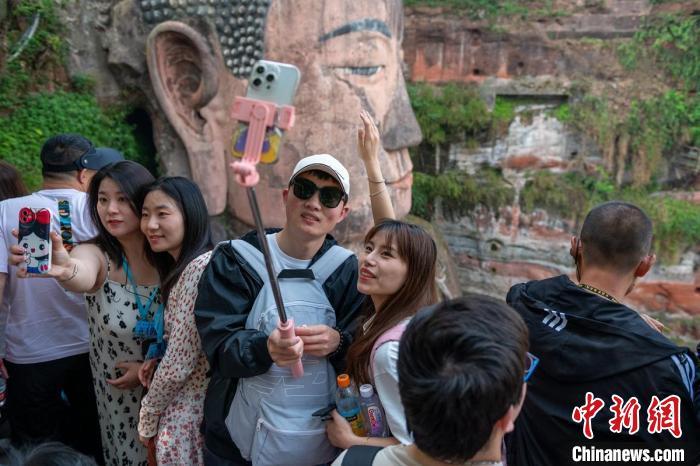 游客用手机与乐山大佛合影。（资料图） 刘忠俊 摄