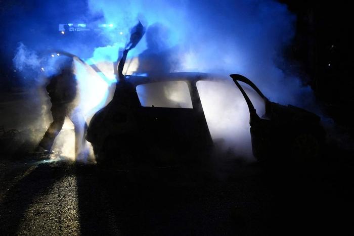 当地时间2023年6月27日，法国楠泰尔，一名消防员走过一辆被抗议者烧毁的冒烟的汽车。图/视觉中国