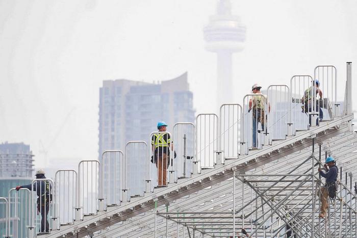 6月28日，加拿大多伦多，工东谈主们正在为多伦多印地赛车大奖赛搭建临时看台，野火的烟雾遮掩了加拿大国度电视塔。