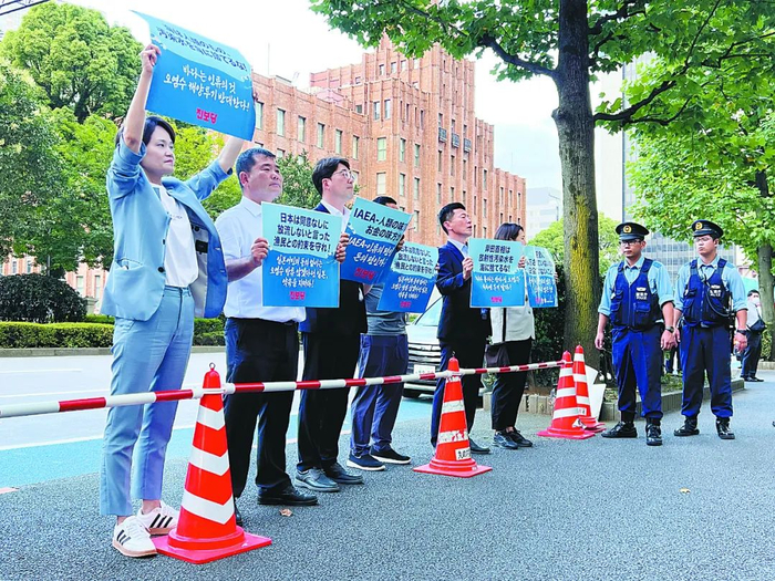 韩国市民团体代表在格罗西记者会的会场外高举标语进行抗议。岳林炜 摄