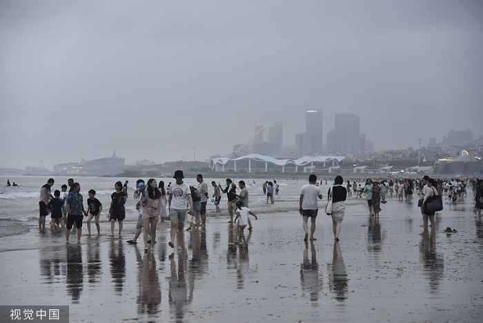 2023年7月2日，青岛石老人海水浴场大雾弥漫，游客沙滩上游玩。 视觉中国 图