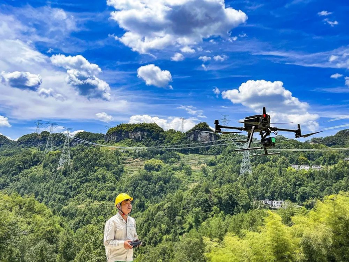 国网重庆超高压公司渝东南运维分部输电运检员工正操作无人机对±800千伏金塘线开展迎峰度夏输电设备通道保电特巡  牟伟摄