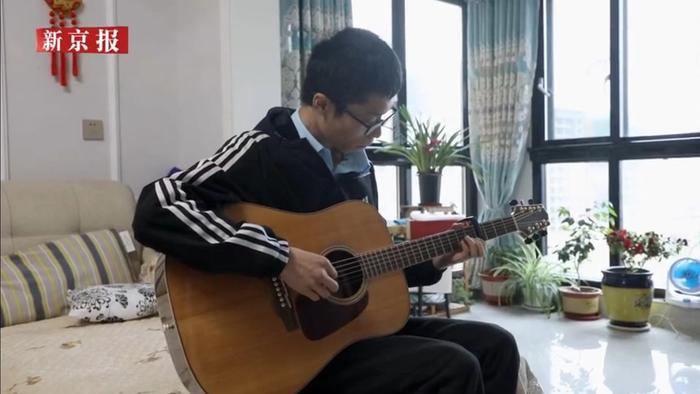 陈泗翰喜欢弹吉他，业余时间也兼职教人弹，他说，音乐是取悦自己的良方。图为新京报记者2021年拍摄的视频截图。