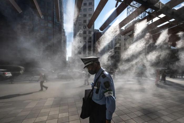 当地时间7月10日，日本东京，一名安保人员走过水雾系统。视觉中国供图