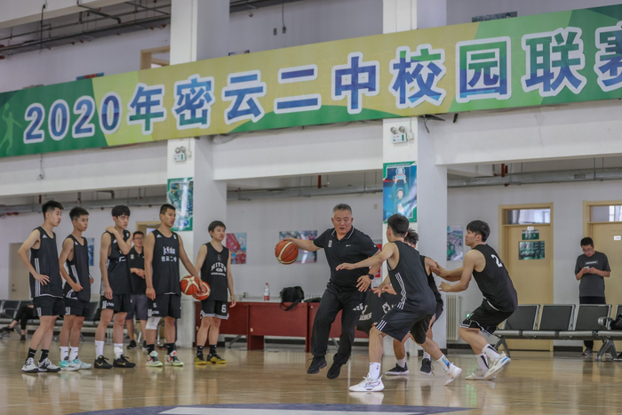 7月11日，北京密云二中篮球馆，密云二中篮球队创始人、总教练张洪斌向队员讲解技术动作并示范。  新京报记者 王子诚 摄