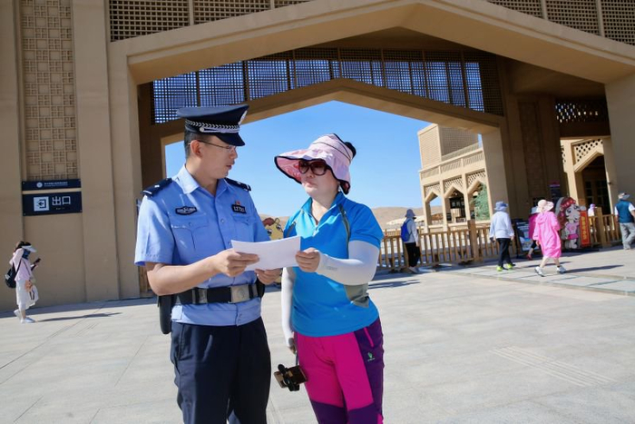 鄯善县公安局民警在景区门口向游客宣传沙漠旅游的安全常识。通讯员艾力亚尔·艾尼 摄