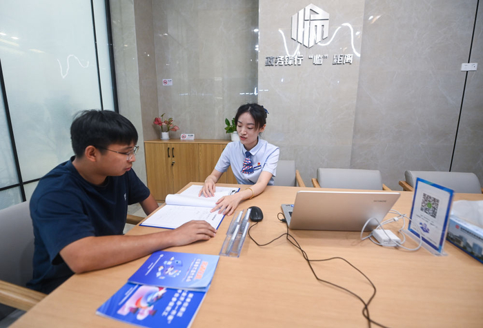 在浙江省杭州市临安区政务服务中心的“为企服务中心”，党员志愿者（右）在解答一名企业主的疑问（7月7日摄）。新华社记者 徐昱 摄