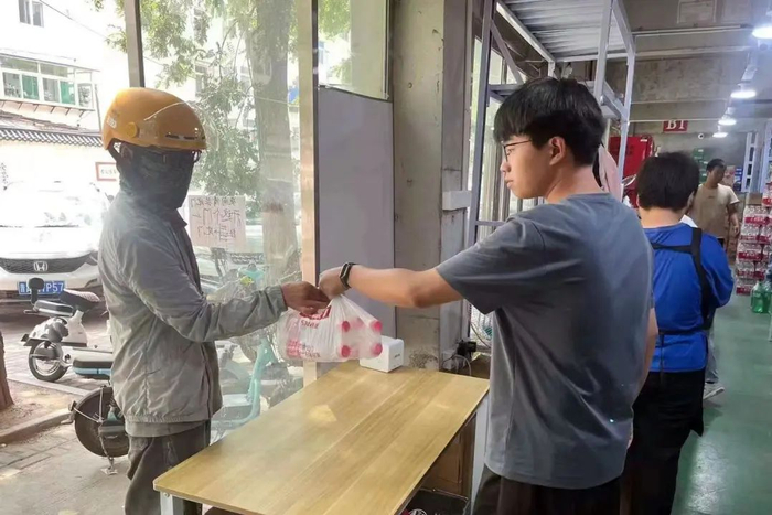 ▲美团闪电仓店员将打包好的商品交给美团骑手