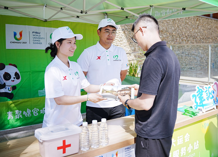 　　7月15日，在成都东部新区三岔湖的成都大运会城市志愿服务小站，志愿者为游客介绍当地旅游资源。新华社记者 王曦 摄