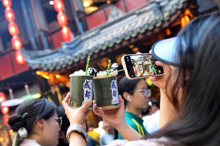 　　7月14日，两名游客在成都锦里用手机拍摄刚刚购买的特色饮品。新华社记者 刘坤 摄