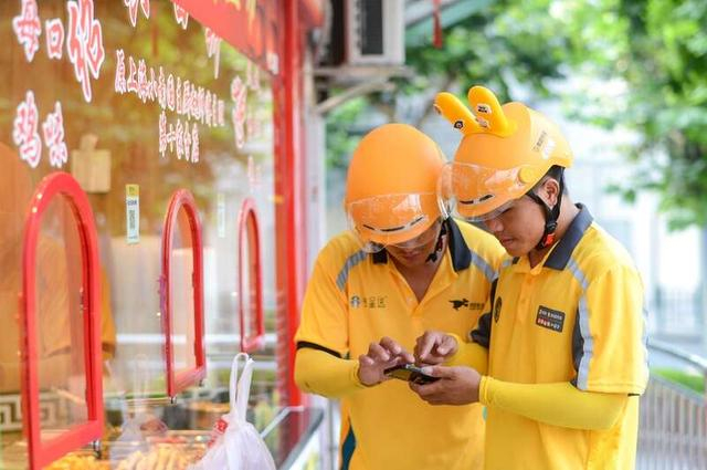 街头某位老骑手在指导徒弟看订单。王佳/摄