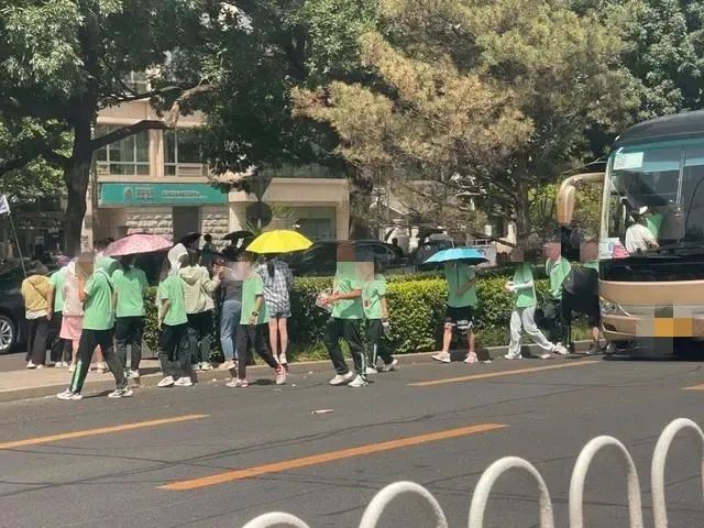 7月5日，前门西公交站附近，从旅游大巴车上下来的学生。新京报记者 吴婷婷 摄