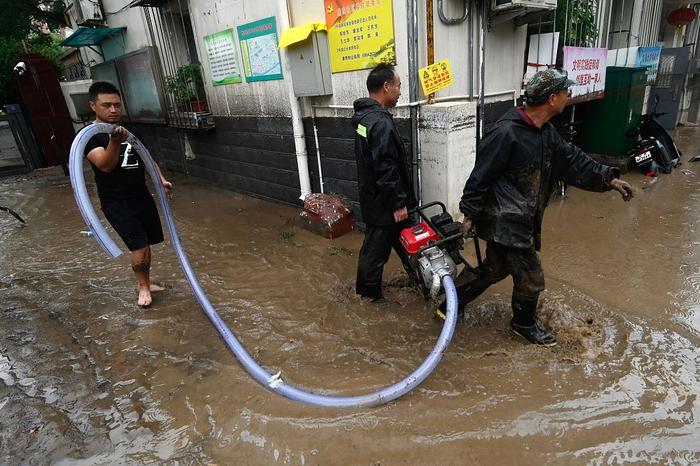 7月31日，北京门头沟区，大雨过后，民众提着水泵沿街排水。