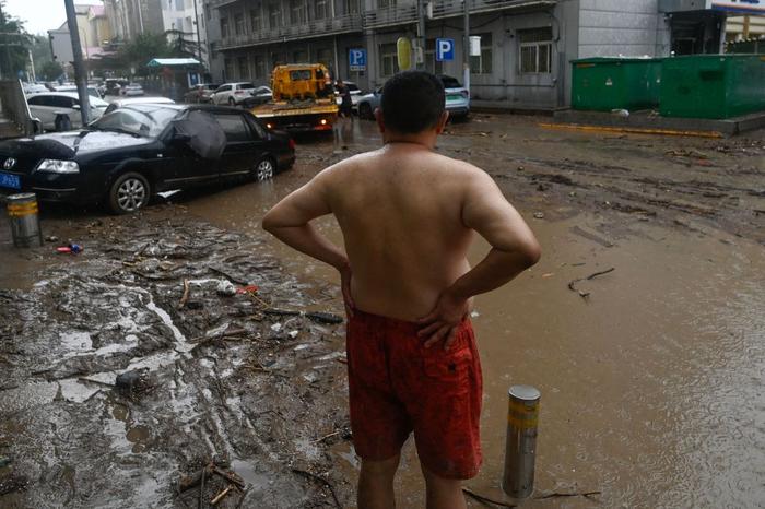 7月31日，北京门头沟，暴雨过后，一名男子站在洪水退去后的道路上。
