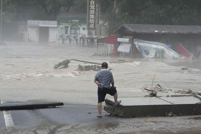 2023年8月1日，北京门头沟妙峰山地区，一名居民眺望被洪水淹没的地区，马路、房屋建筑被洪水淹没。
