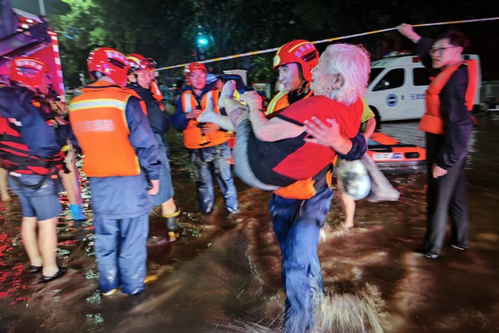 消防队员抱着老人离开积水区。