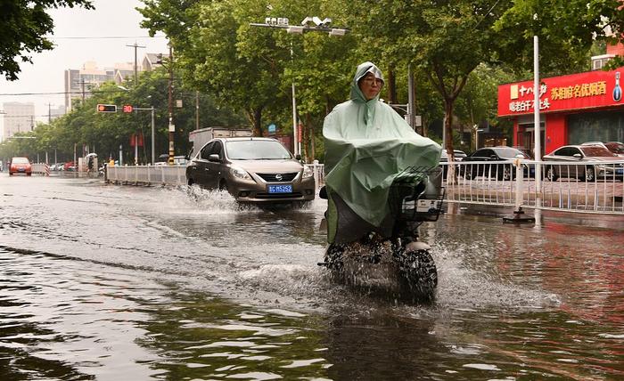 图为7月31日，市民在石家庄市栾城区街头冒雨出行。图/视觉中国