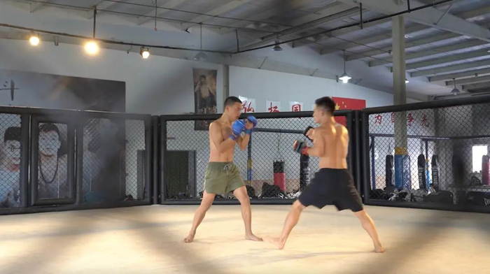 ▲7月10日，两名运动员在八角笼中打实战，笼外的墙上挂着一排赢得过荣誉的运动员的巨幅画像。新京报记者徐雪飞摄