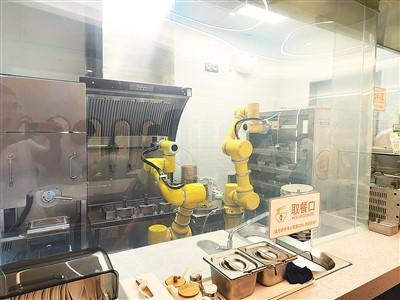 6月26日，在上海市世贸商城二楼AI智慧食堂“小Q饭堂”的开放式厨房内，机器人正在有条不紊地准备饭菜。记者 杨俊峰摄