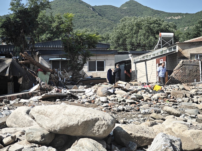 8月13日，北京门头沟，受灾后的潭柘寺镇南辛店村，村民在院子里晾晒衣服，院子里堆满了被洪水冲上来的石块。
