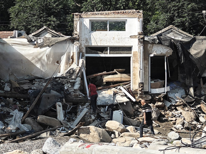 8月13日，北京门头沟，受灾后的潭柘寺镇南辛店村，村民踩着横七竖八的石块返回村中。