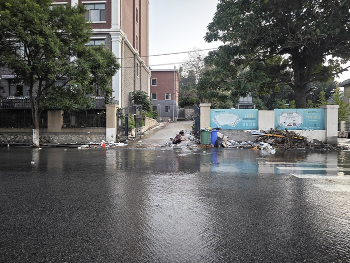 8月13日，北京门头沟，受灾后的王平镇，在镇政府对面，一位居民在马路边洗鞋子。