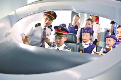 “小列车长”们在南京东机辆段动车运用车间参观模拟驾驶台。新华社发