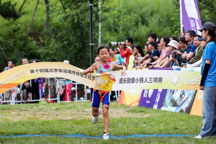 参加第十四届北京奥运城市体育文化节成长勋章小铁人三项赛的小选手在跑步项目比赛中冲刺撞线。北京奥运城市发展促进中心供图