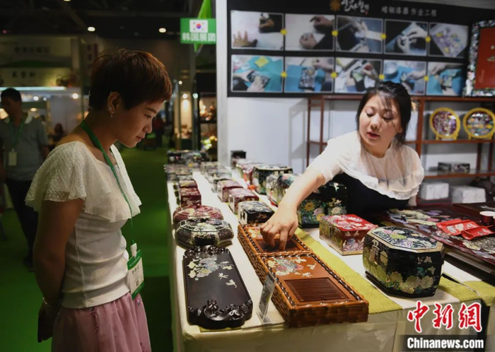 在浙江杭州举行的第二届中国国际茶叶博览会上，一名参观者被展出的韩国茶器吸引。王刚 摄